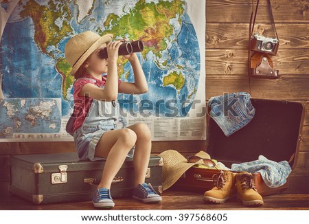 happy baby girl getting ready for the journey. Girl packs her bags and playing with binoculars.