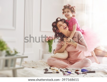 Happy loving family. Mother and daughter are doing hair and having fun. Mother and her child girl playing and hugging.