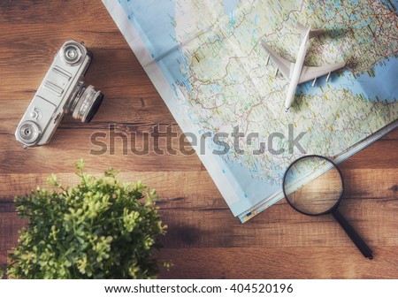 Go on an adventure! The map and the camera on a wooden table. Top view.