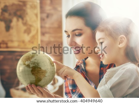 Go on an adventure! Happy family preparing for the journey. Mom and daughter study the globe and choose a route of travel.