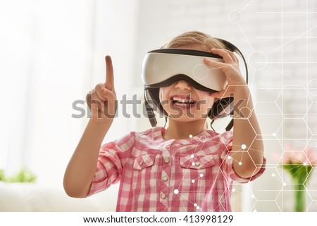 Cute little child girl playing game in virtual reality glasses.