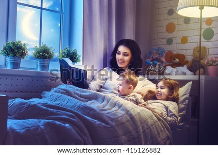 Family reading bedtime. Pretty young mother reading a book to her daughters.