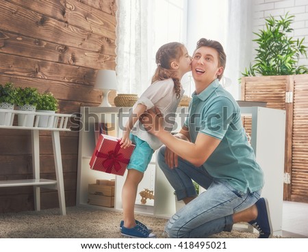 Happy loving family and Father's Day. Father and his daughter. Cute child girl kisses dad and gives him a gift.