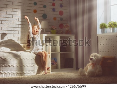 A nice child girl enjoys sunny morning. Good morning at home. Child girl wakes up from sleep.