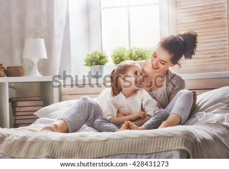 Happy loving family. Mother and her daughter child girl playing in bed.