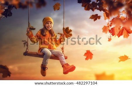 Happy child girl on swing in sunset fall. Little kid playing in the autumn on the nature walk.
