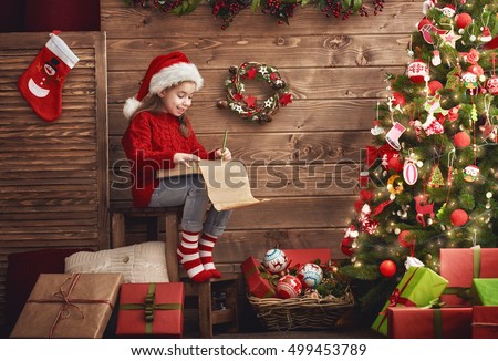 Merry Christmas! Cute little child girl writes the letter to Santa Claus.