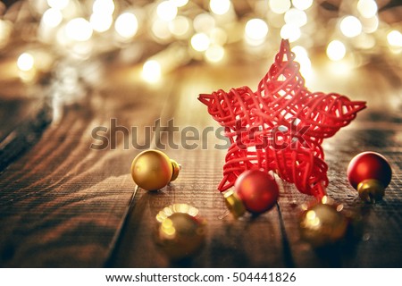 Merry Christmas and Happy Holidays! Red star, Christmas baubles and garland lights on old dark wooden rustic background.