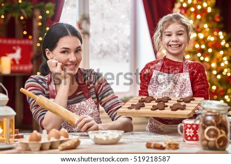 Merry Christmas and Happy Holidays. Family preparation holiday food. Mother and daughter cooking Christmas cookies.