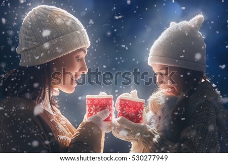 Happy loving family! Mother and child girl drinking tea on snowy winter walk in nature. Frost winter season.