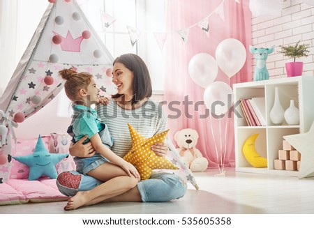 Happy loving family. Mother and her daughter girl play in children room. Funny mom and lovely child having fun indoors.