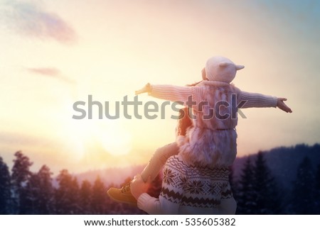 Happy loving family! Father and his daughter are playing and hugging outdoors. Cute little girl and daddy on snowy winter walk in nature. Concept of frost winter season.
