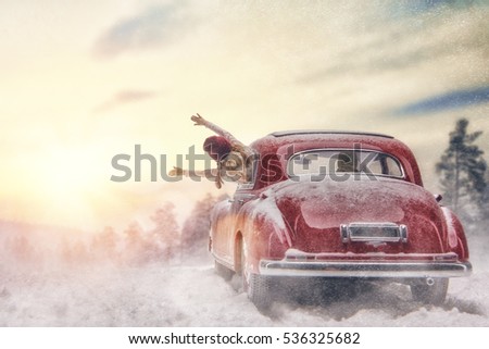 Toward adventure! Happy family relaxing and enjoying road trip. Parent, child and vintage car on snowy winter nature background. Christmas holidays time.