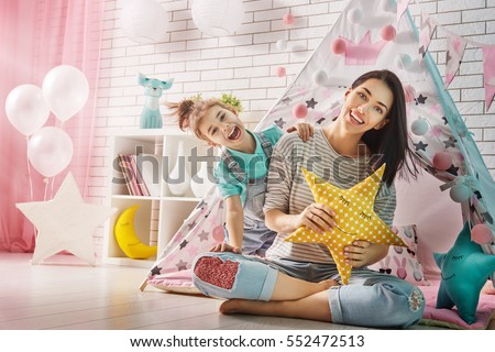 Happy loving family. Mother and her daughter girl play in children room. Funny mom and lovely child having fun indoors.