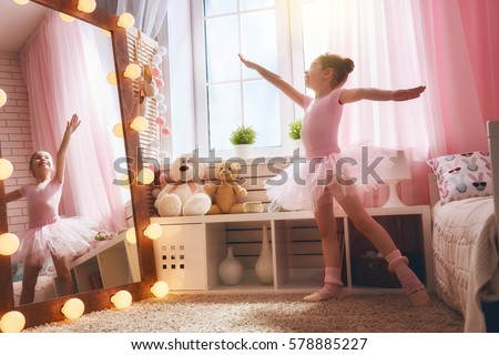 Cute little girl dreams of becoming a ballerina. Child in a pink tutu dancing in a kids room.