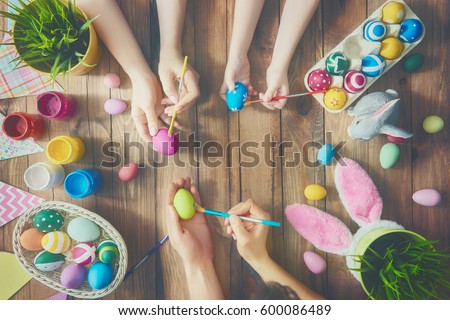 A mother, father and their child painting eggs. Happy family preparing for Easter.