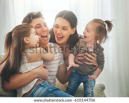 Happy father\'s day! Two children daughters with mother congratulate daddy. Mum, dad and girls laughing and hugging. Family holiday and togetherness.