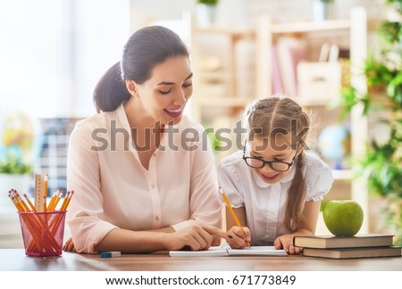 Happy school time. Mother and daughter are learning to write. Adult woman teaches child the alphabet.
