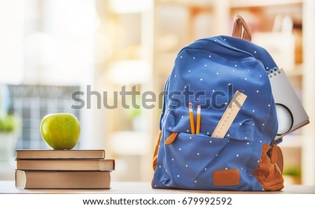 Back to school and happy time! Apple, pile of books and backpack on the desk at the elementary school.