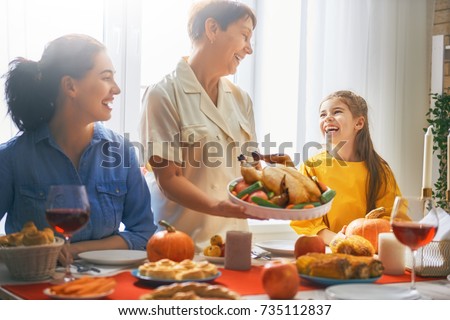 Happy Thanksgiving Day! Autumn feast. Family sitting at the table and celebrating holiday. Traditional dinner. Grandmother, mother and daughter.