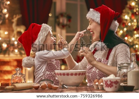 Merry Christmas and Happy Holidays. Family preparation holiday food. Mother and daughter cooking cookies.
