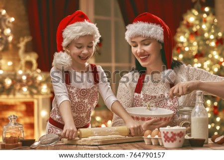 Merry Christmas and Happy Holidays. Family preparation holiday food. Mother and daughter cooking cookies.