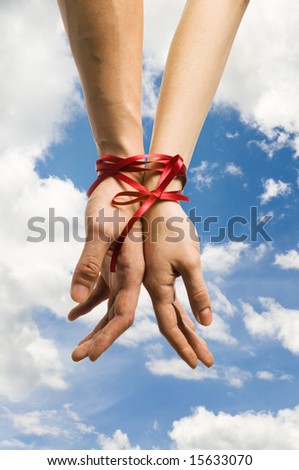 mans and  girls hands tieing with ribbon