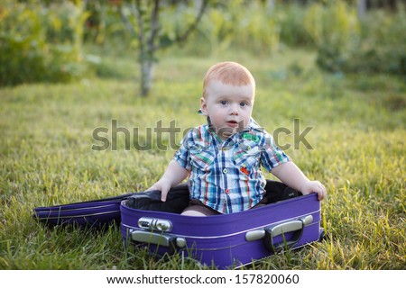 Small boy sitting on an old suitcase