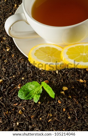 White cup of tea next to a green leaf