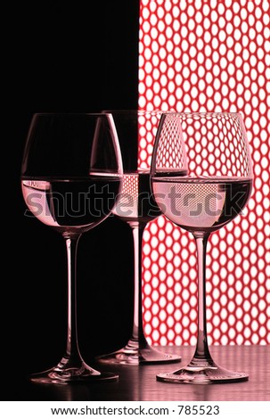 three wine glasses in backlight on the black and white contrast background over red grid