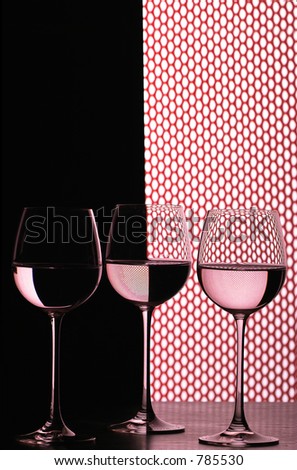 three wine glasses in backlight on the black and white contrast background with red grid fish net