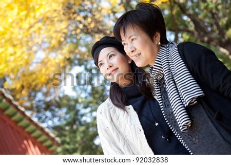 smiling asian mother and young daughter looking up with autumn background taken in a park ,Korea