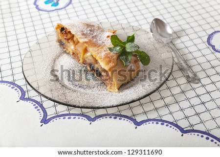 Slice of apple strudel powdered with icing sugar on a plate