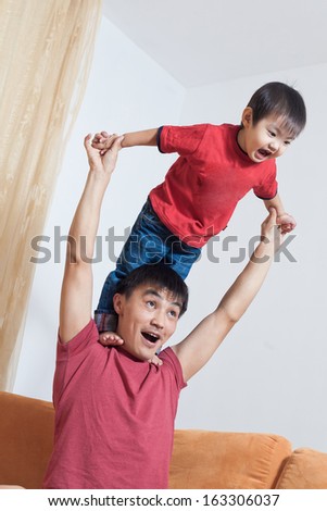 Asian father and son kissing and playing