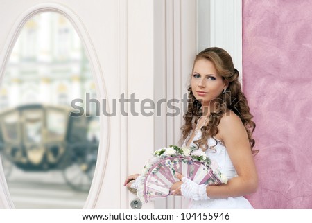 Bride with wedding fan-bouquet near the mirror