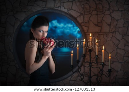 Fantasy style portrait of demonic woman biting a pomegranate