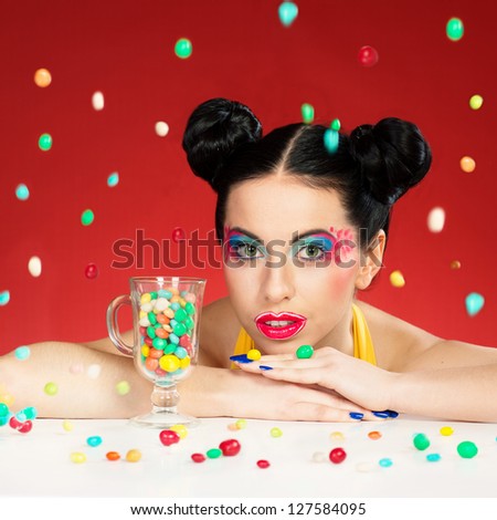 Portrait of funny woman with colorful makeup under the falling candy drops