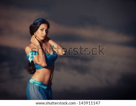 Eastern style portrait of a beautiful girl in belly dance costume at sunset