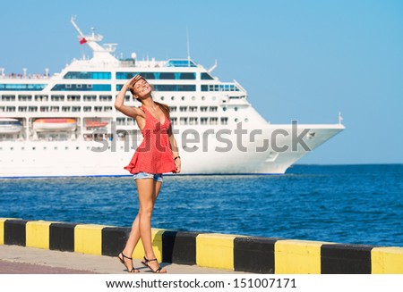 Young woman walking along the quay, the ship sailing by