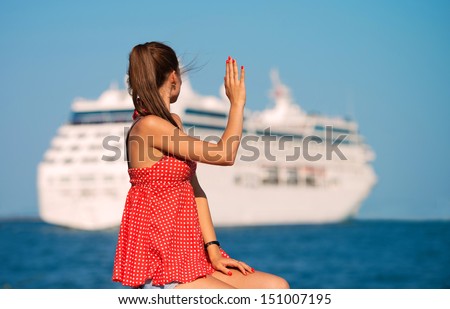 Young woman looking at the ship and waving her hand, view from the back