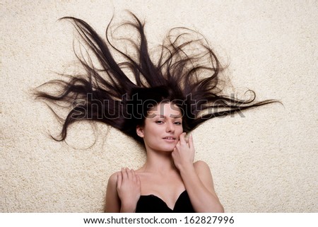 Portrait of a woman with long brown hair lying on the floor, view from above