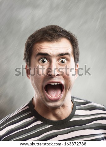 Man screams opening the mouth, close-up shot, abstract gray background