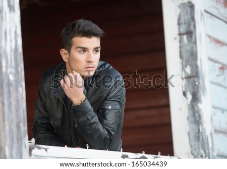 Portrait of a handsome young man at the old wooden window