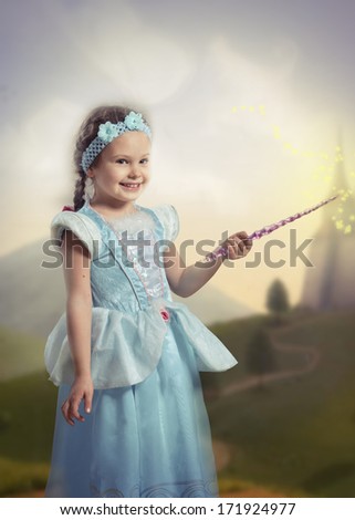 Portrait of a smiling girl in blue dress with a magic wand in her hand, fairy tale landscape on background