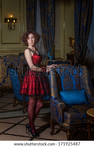Full-length portrait of a woman in red cocktail dress in luxury interior