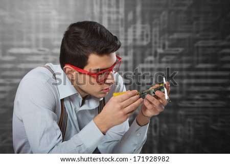 Man in red-framed glasses fixing an electronic card
