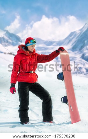 Woman holding snowboard with mountains in background