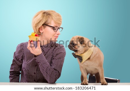 Pretty woman stopping her dog from eating cake