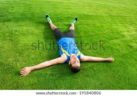 Tired athletic man lying on the grass
