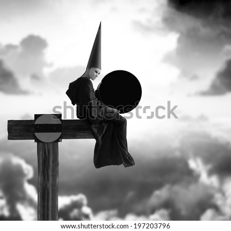 Eclipse. Strange person in black cloak and dunce hat with dark moon in her hands. Black and white image